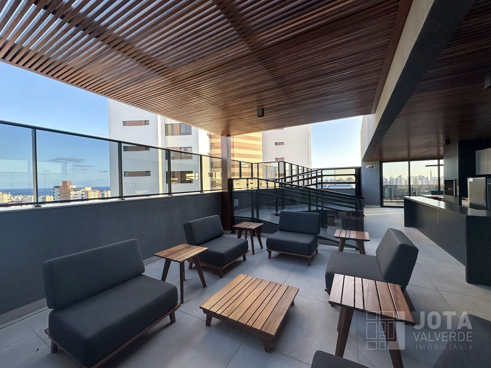 Lounge coberto da cobertura, com poltronas, forro de madeira e vista para o mar